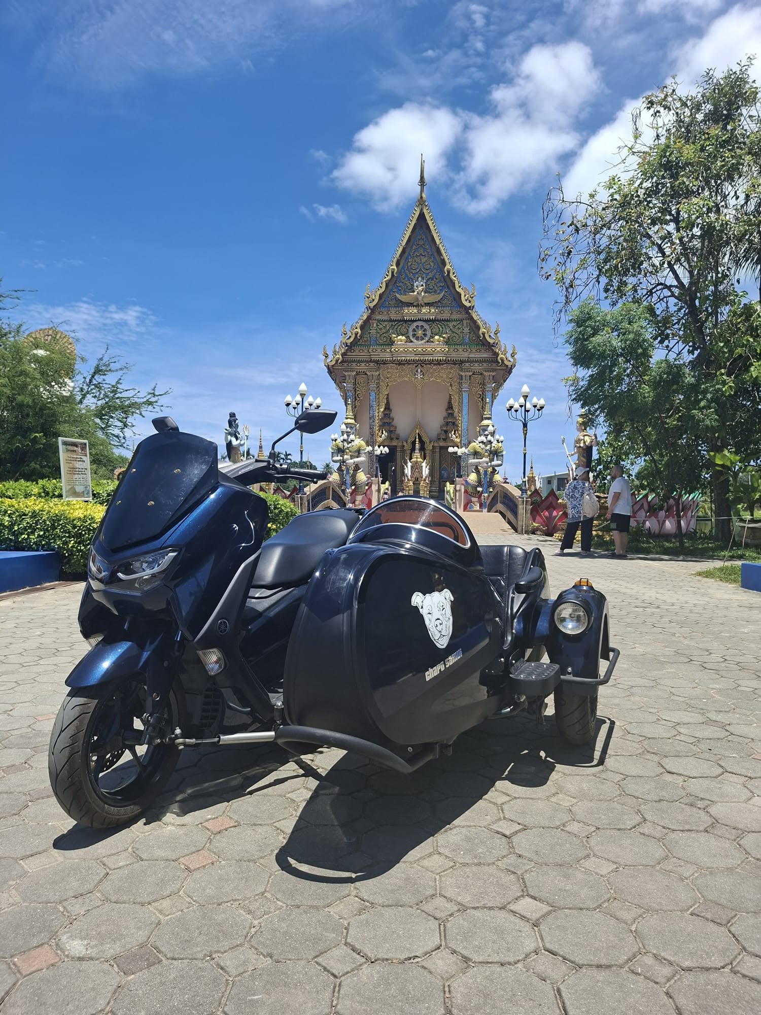 Blue Chapo Samui sidecar parked in front of a traditional Thai temple in Koh Samui