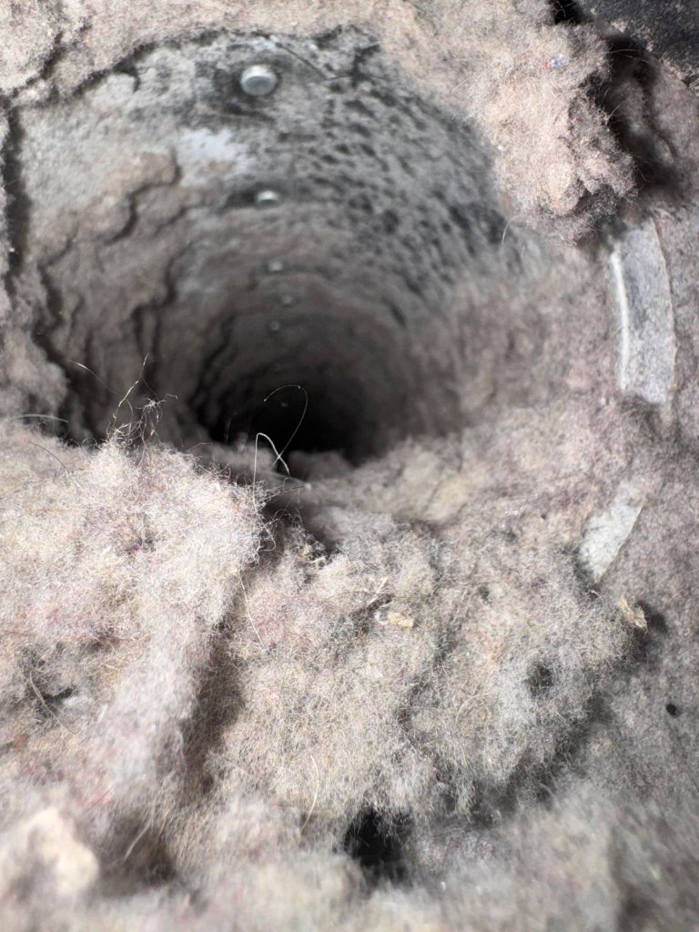 Before: Dangerously clogged dryer vent packed with lint