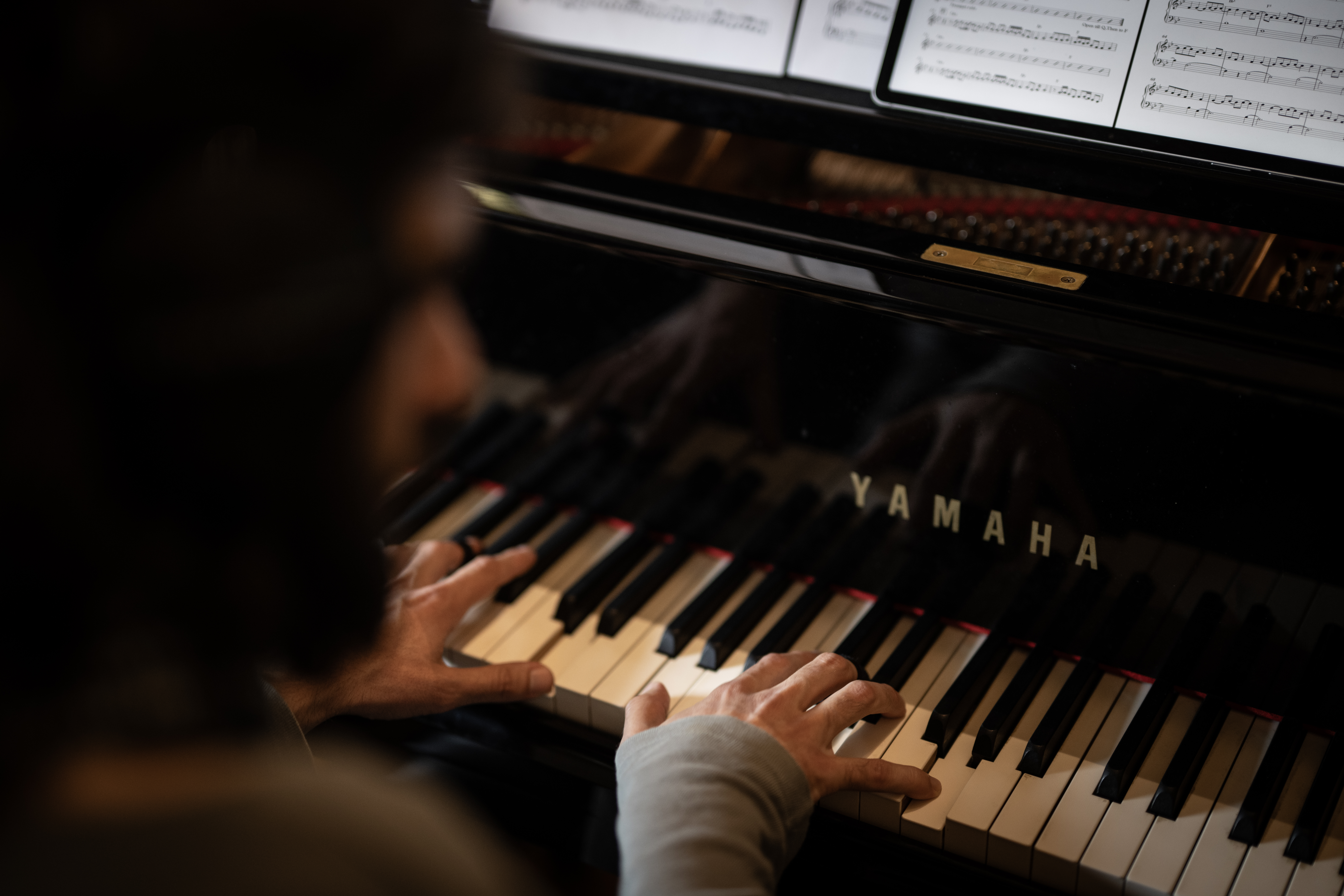 The pianist’s hands on the piano keys, with sheet music above.