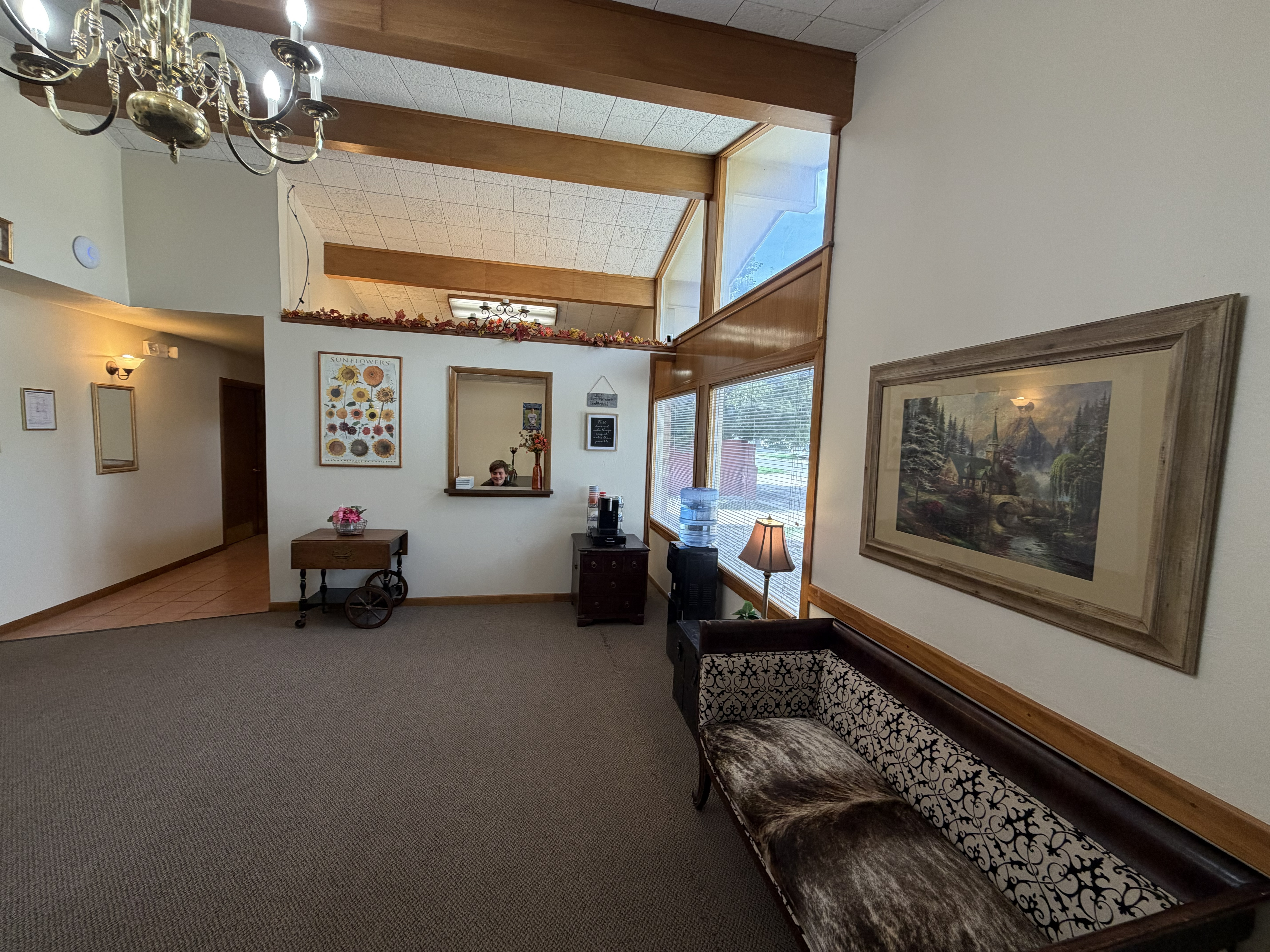 Wellspring Healthcare waiting room with warm wood beams, brass chandelier, and comfortable seating