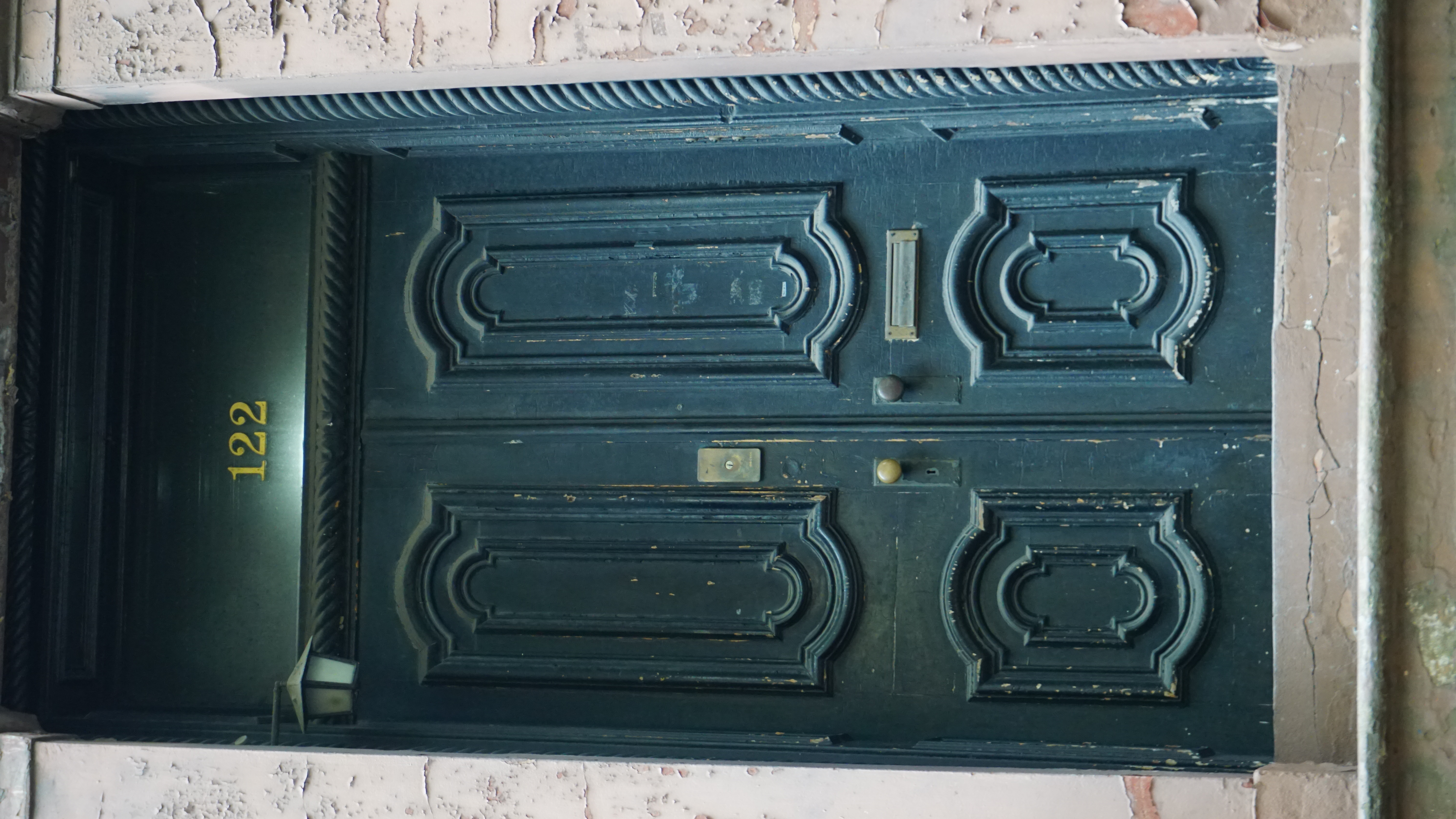Historic dark green doorway with ornate panels and brass hardware