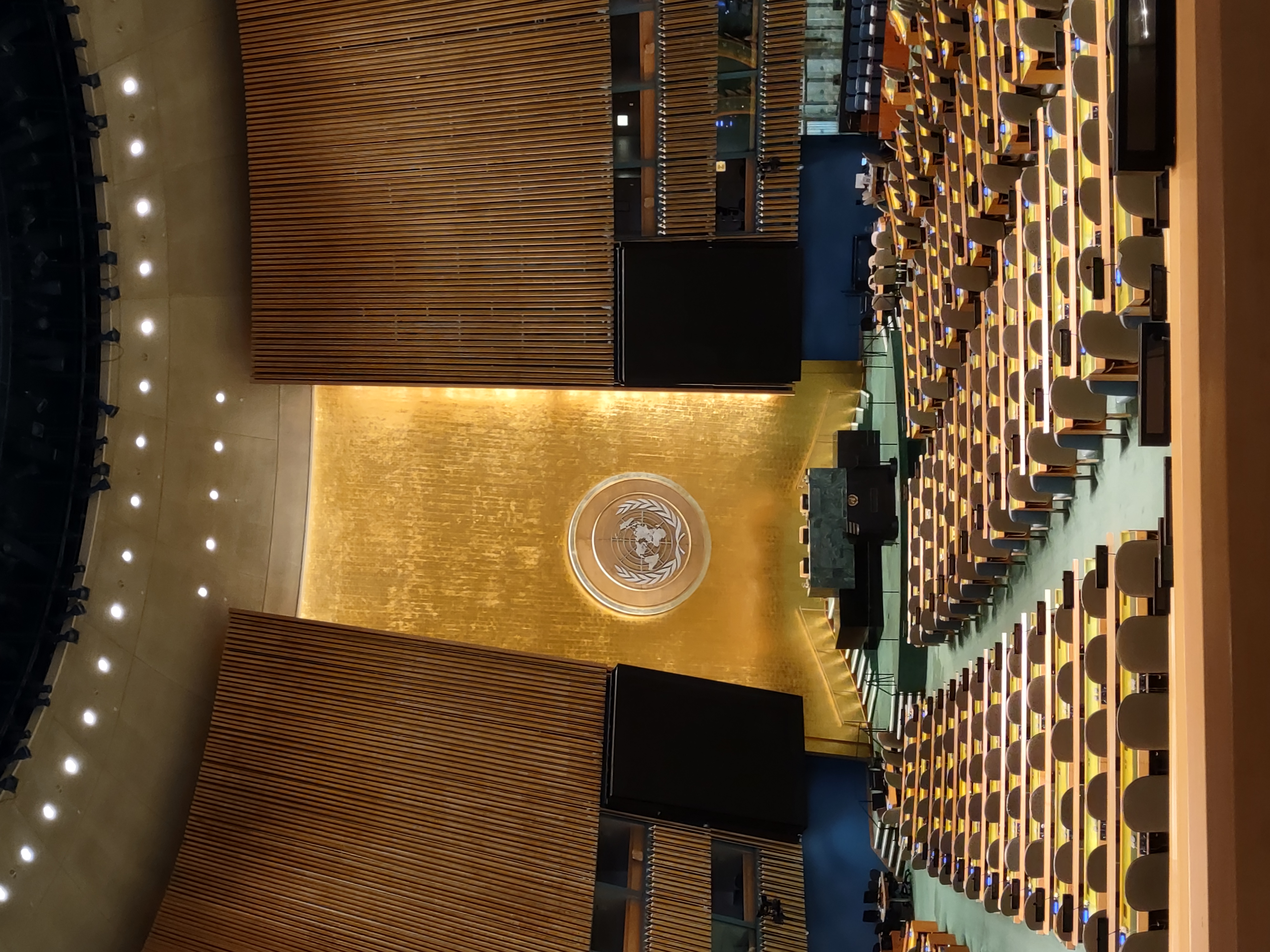 Interior of the United Nations General Assembly Hall with gold wall and UN emblem