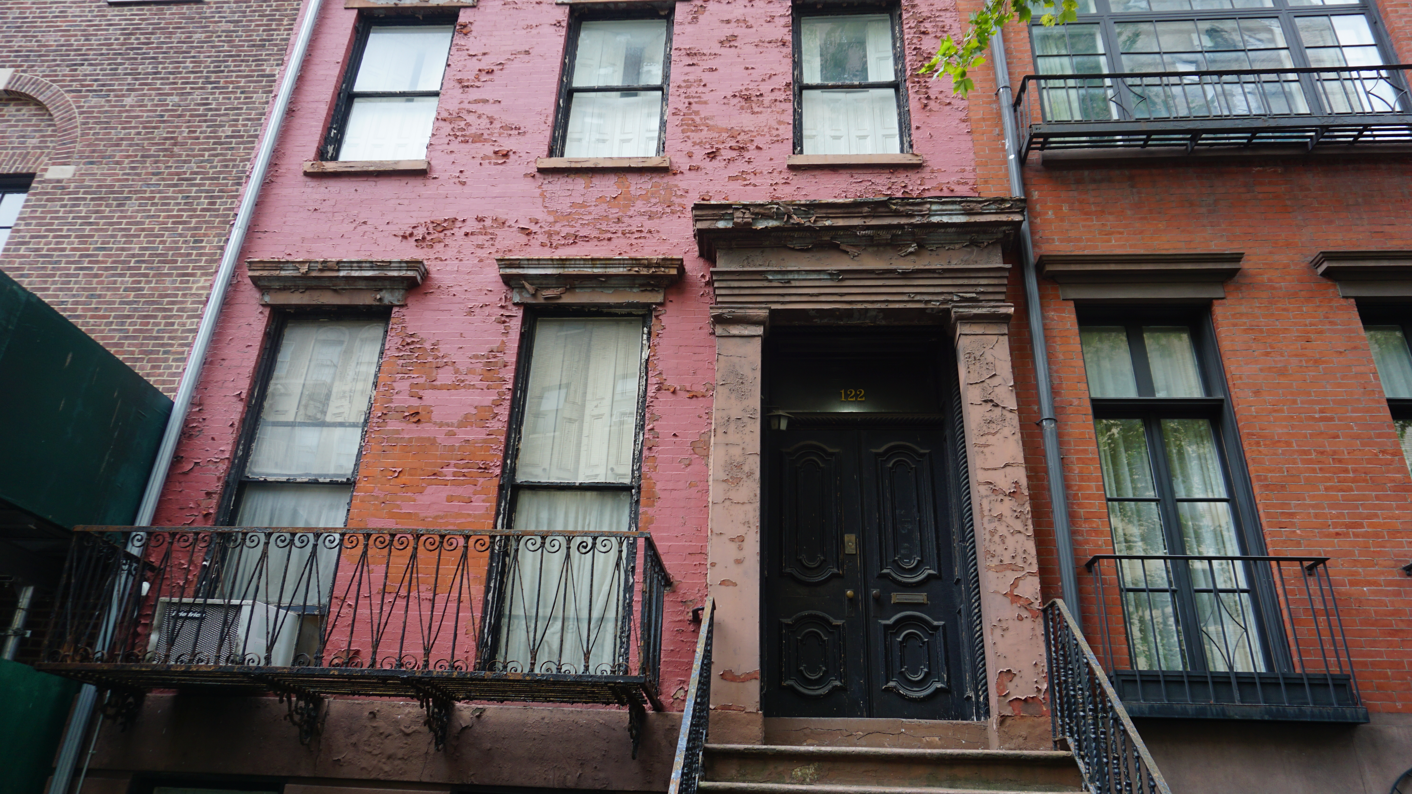 Four-story rose-pink townhouse with wrought-iron balcony