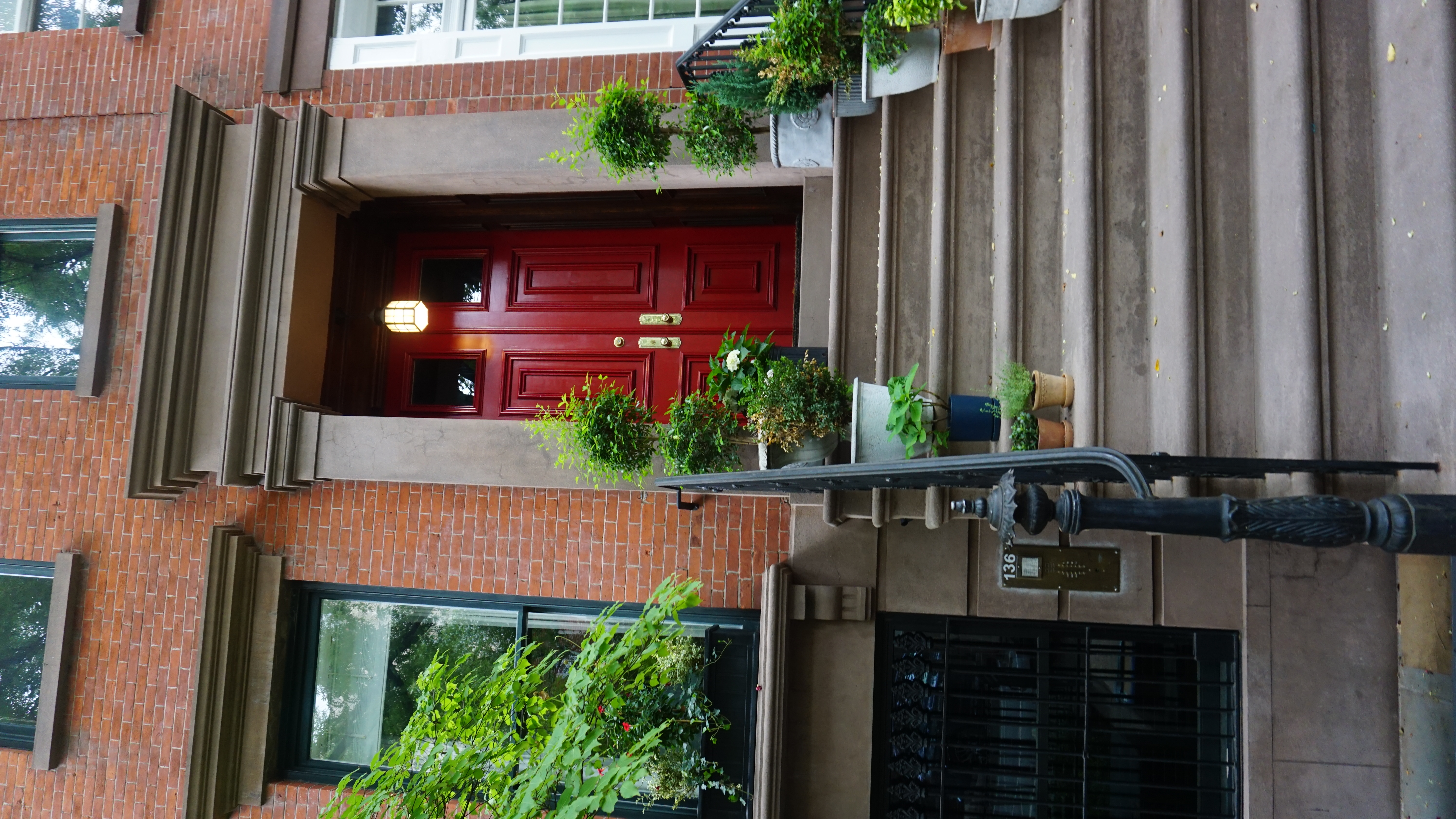 Classic red brownstone door with stone steps and potted plants