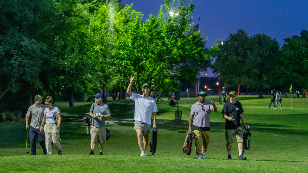 Members walking the course at twilight