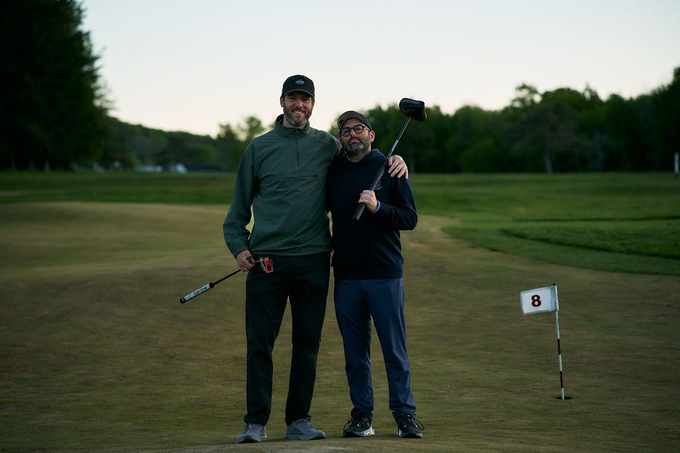 Two members arm in arm on the 8th green at dusk