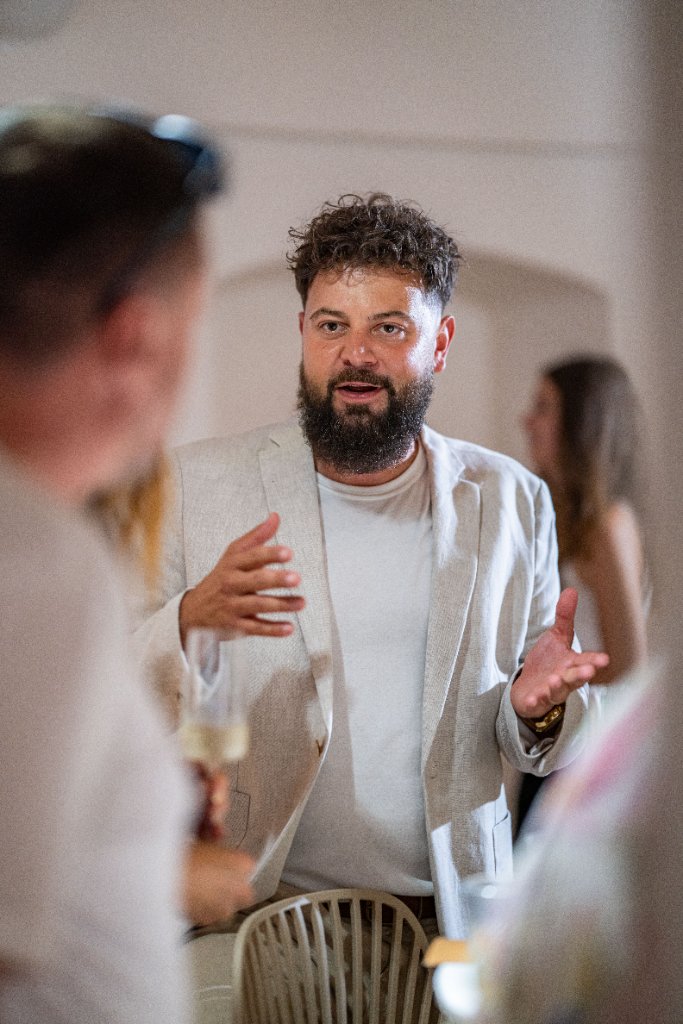 Opening , muž v béžovém saku gestikuluje