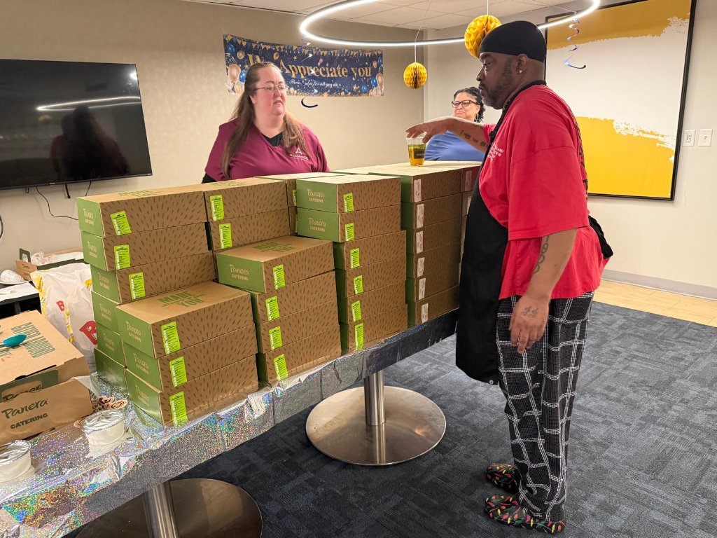 Staff member distributing Panera Catering boxes at appreciation event