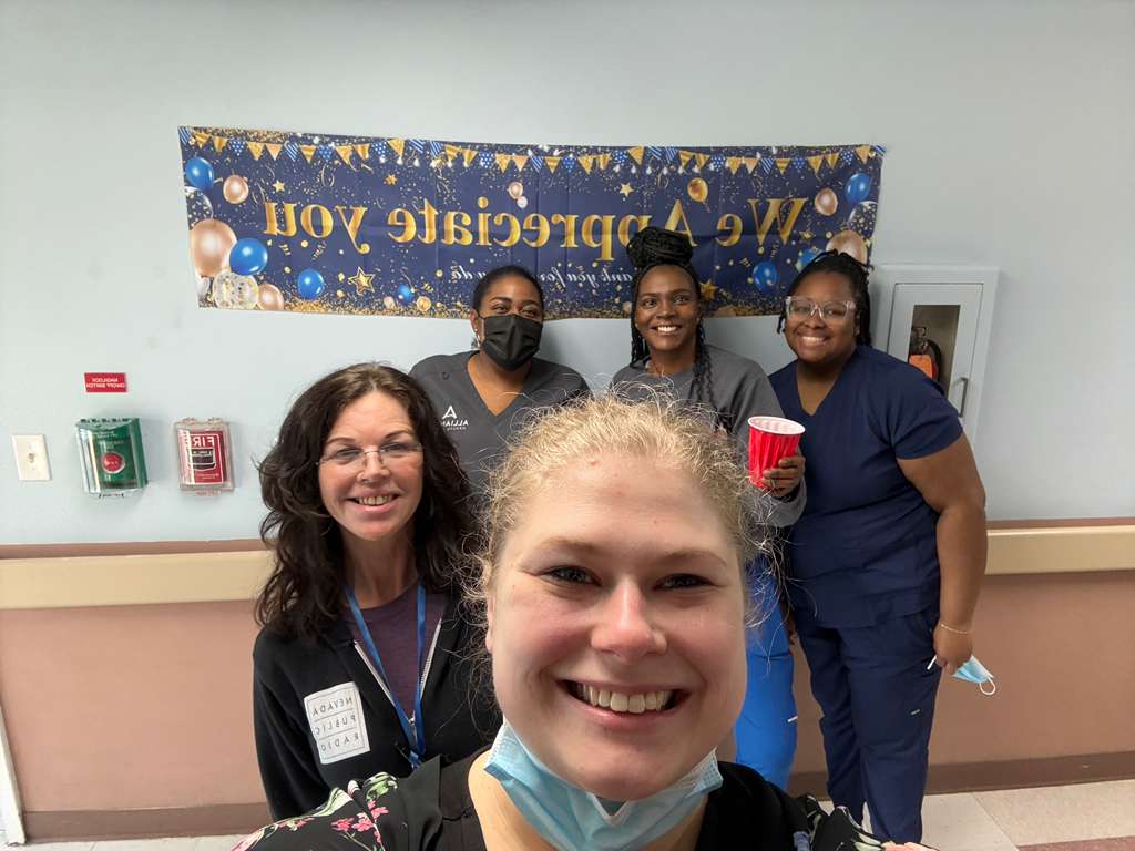 Team selfie in front of We Appreciate You banner