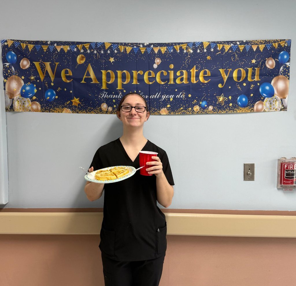 Staff member smiling in front of We Appreciate You banner