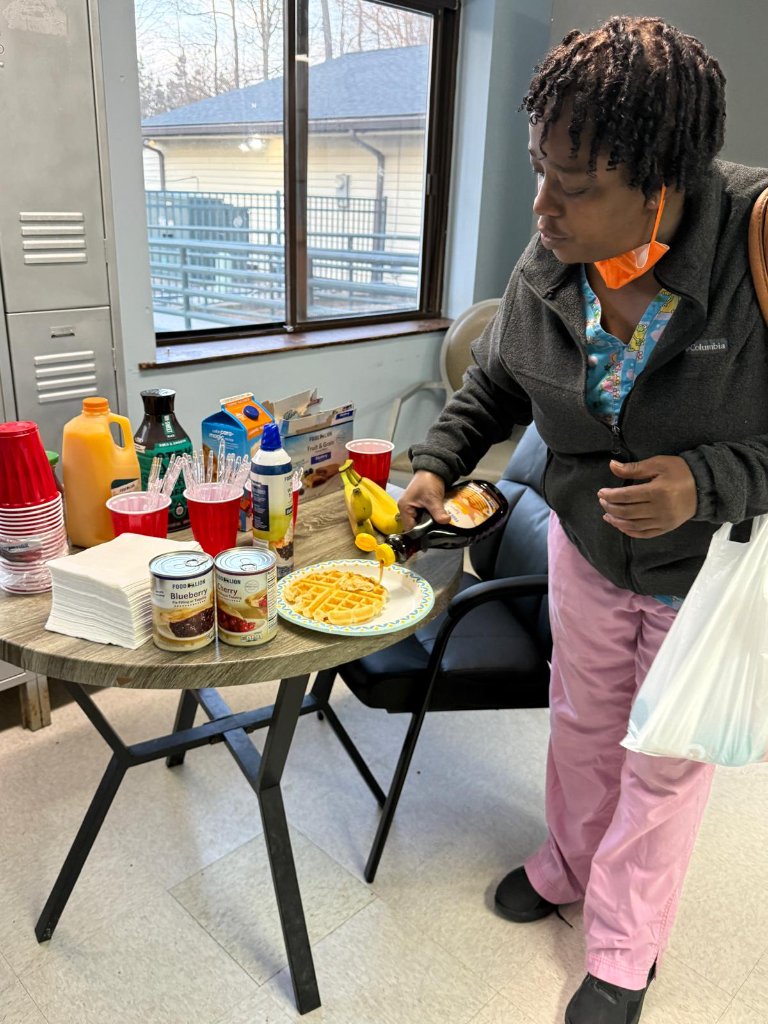 Employee adding syrup to waffles at appreciation breakfast