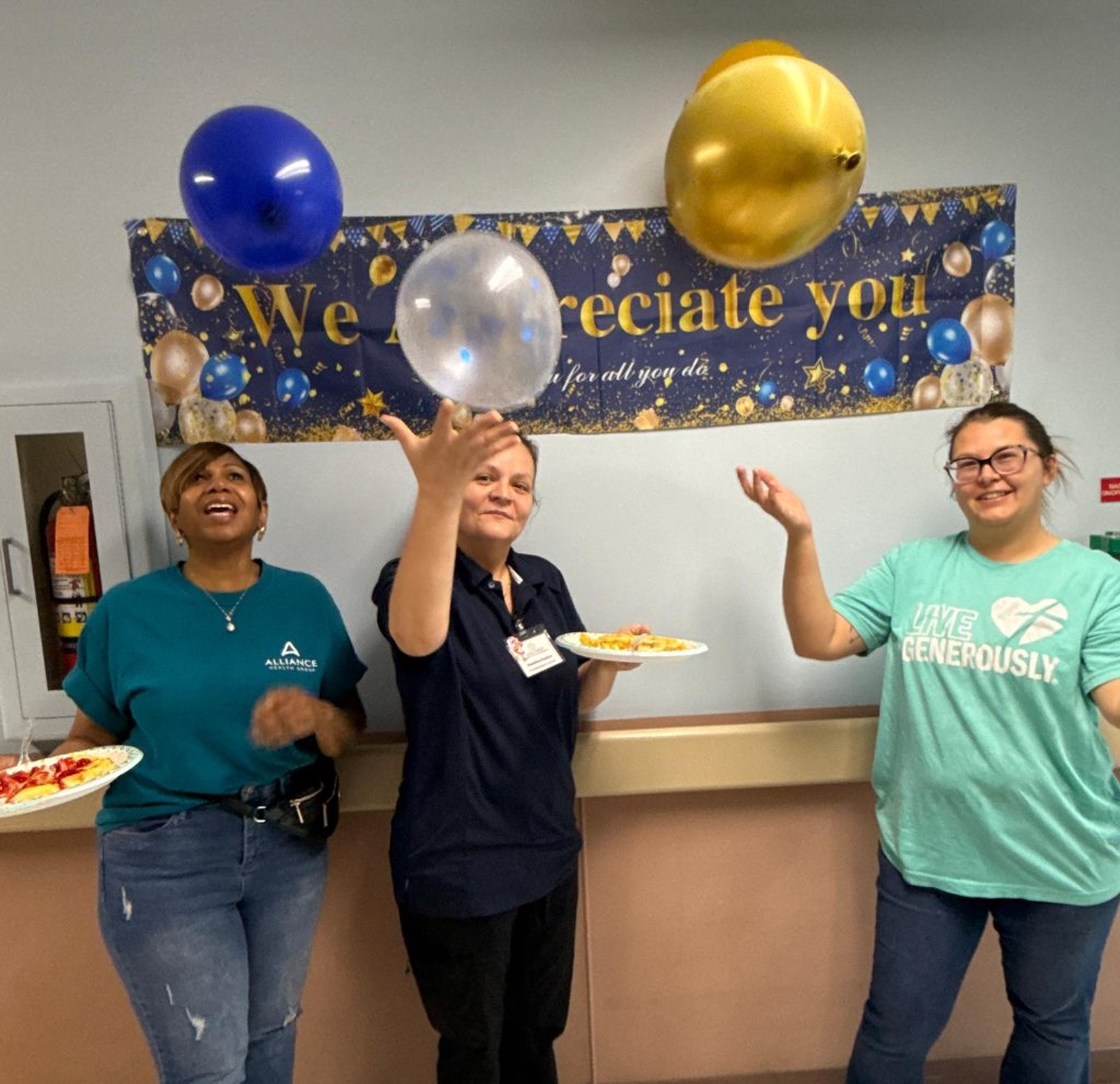 Staff members throwing balloons in front of We Appreciate You banner at Employee Appreciation Week.