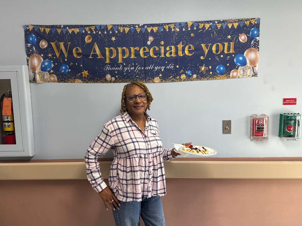 Staff member posing with a plate of food at appreciation week