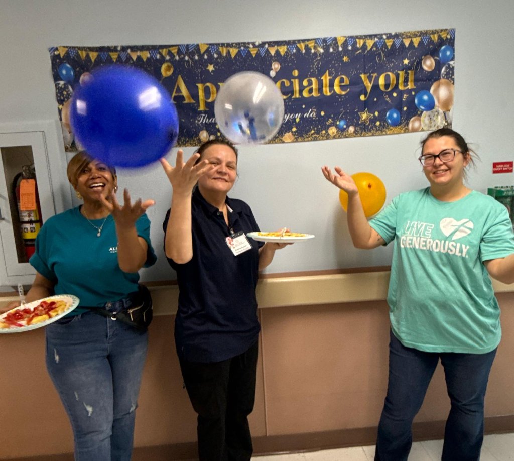 Three staff members playing with balloons at appreciation week