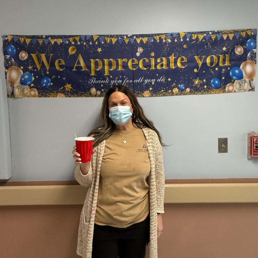 Staff member in Mill Creek shirt holding a red cup at appreciation event