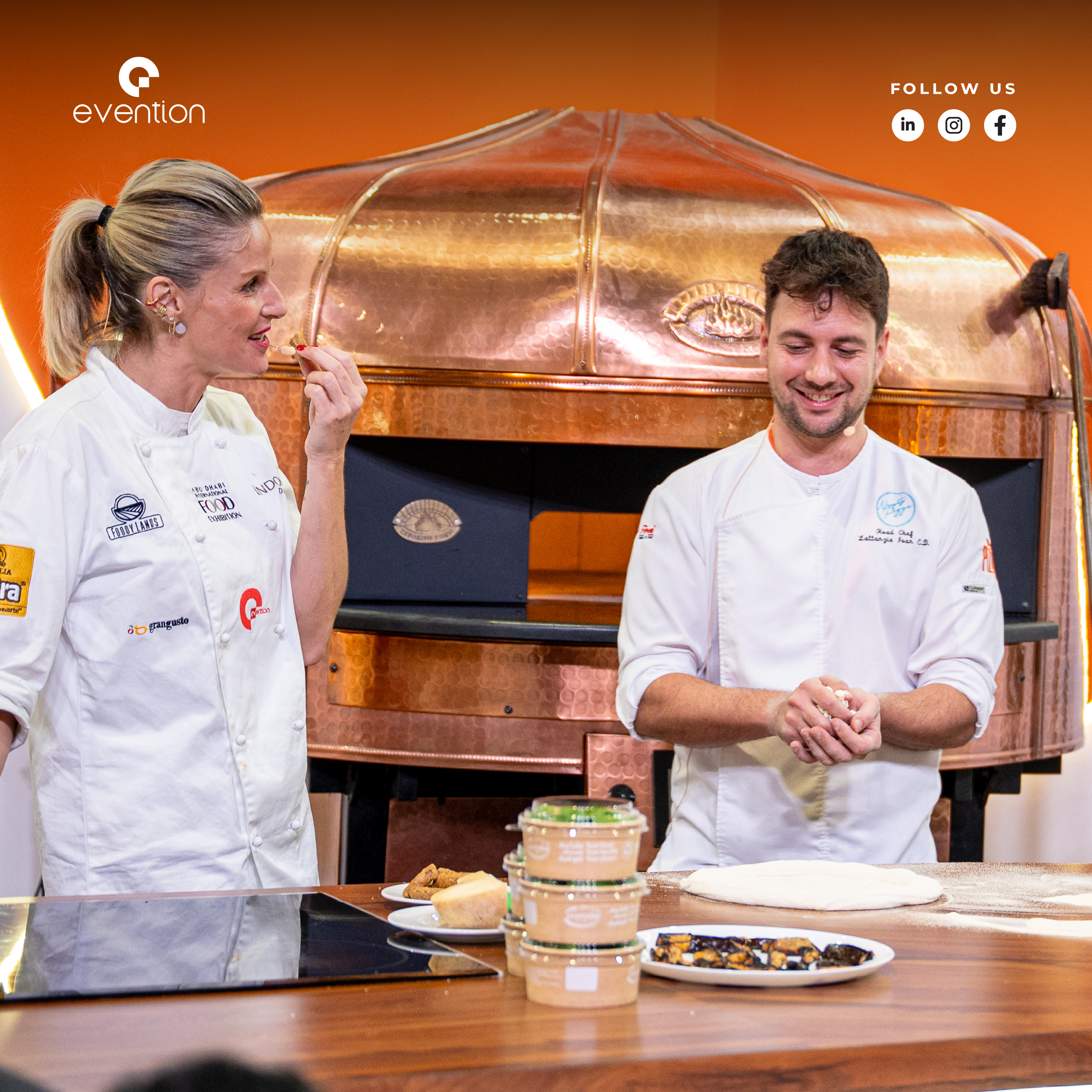 Two chefs preparing pizza beside a copper oven at World Gourmet Show 2025