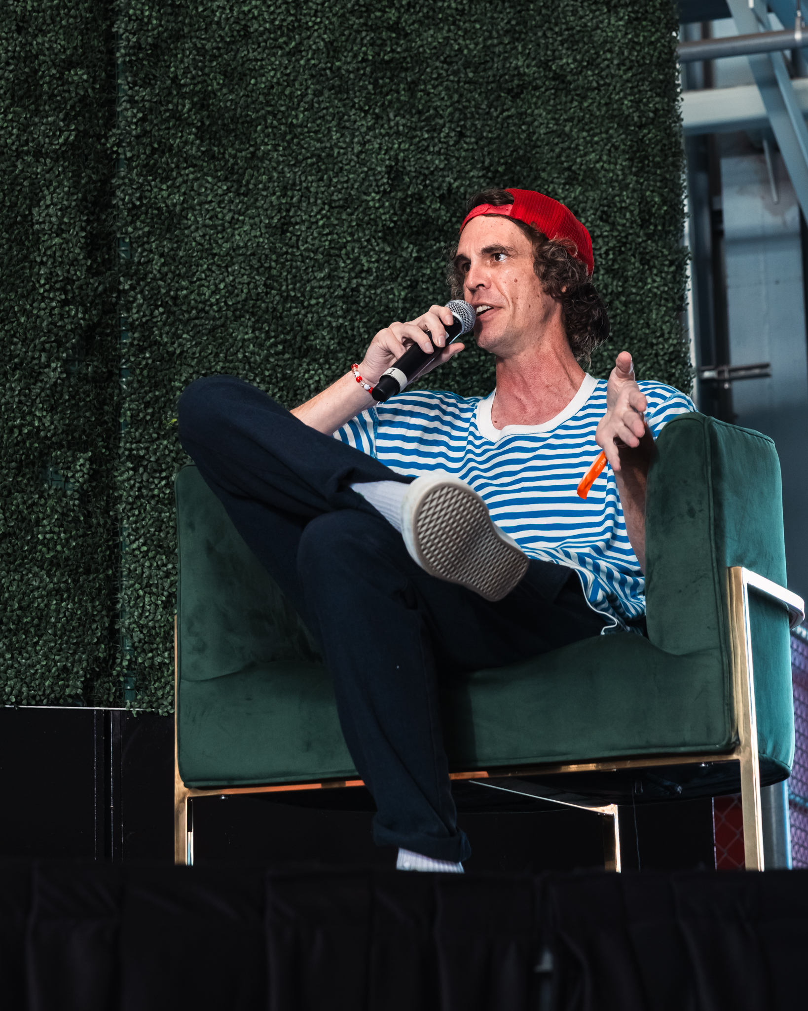 Panelist in a striped shirt and red cap speaking on stage