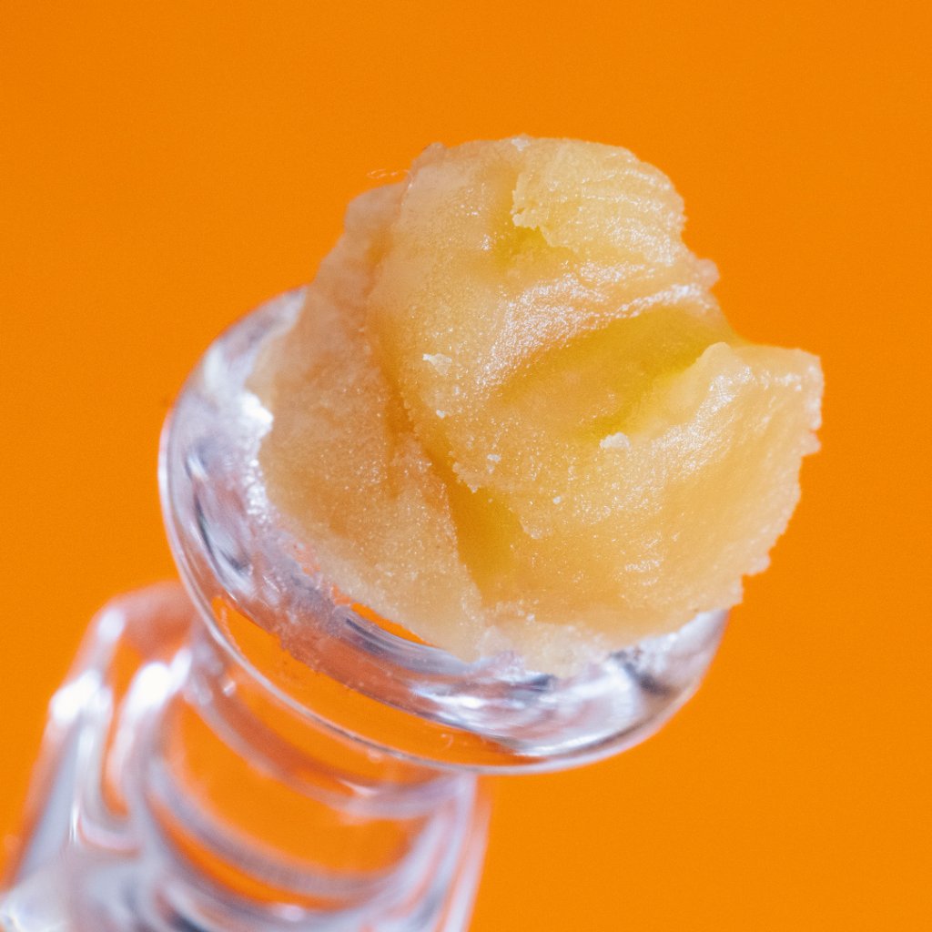 Golden wax resting on a quartz banger against a bright orange background