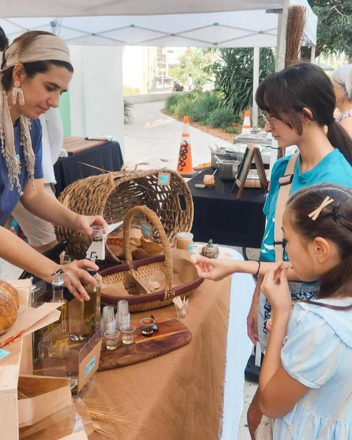 A vendor offering a sample to a customer at an outdoor market stall