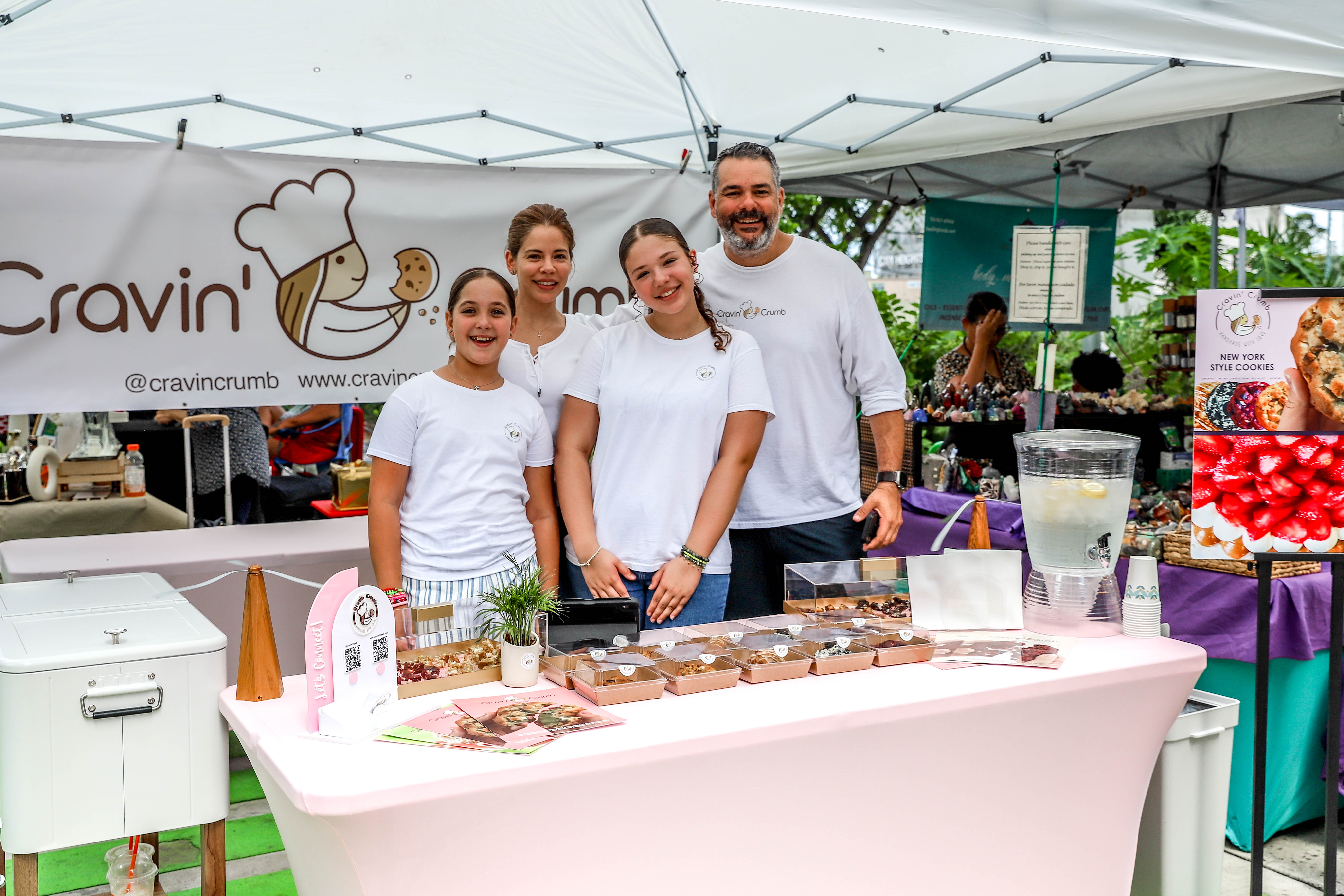 A family-run bakery booth set up under a canopy tent at a market