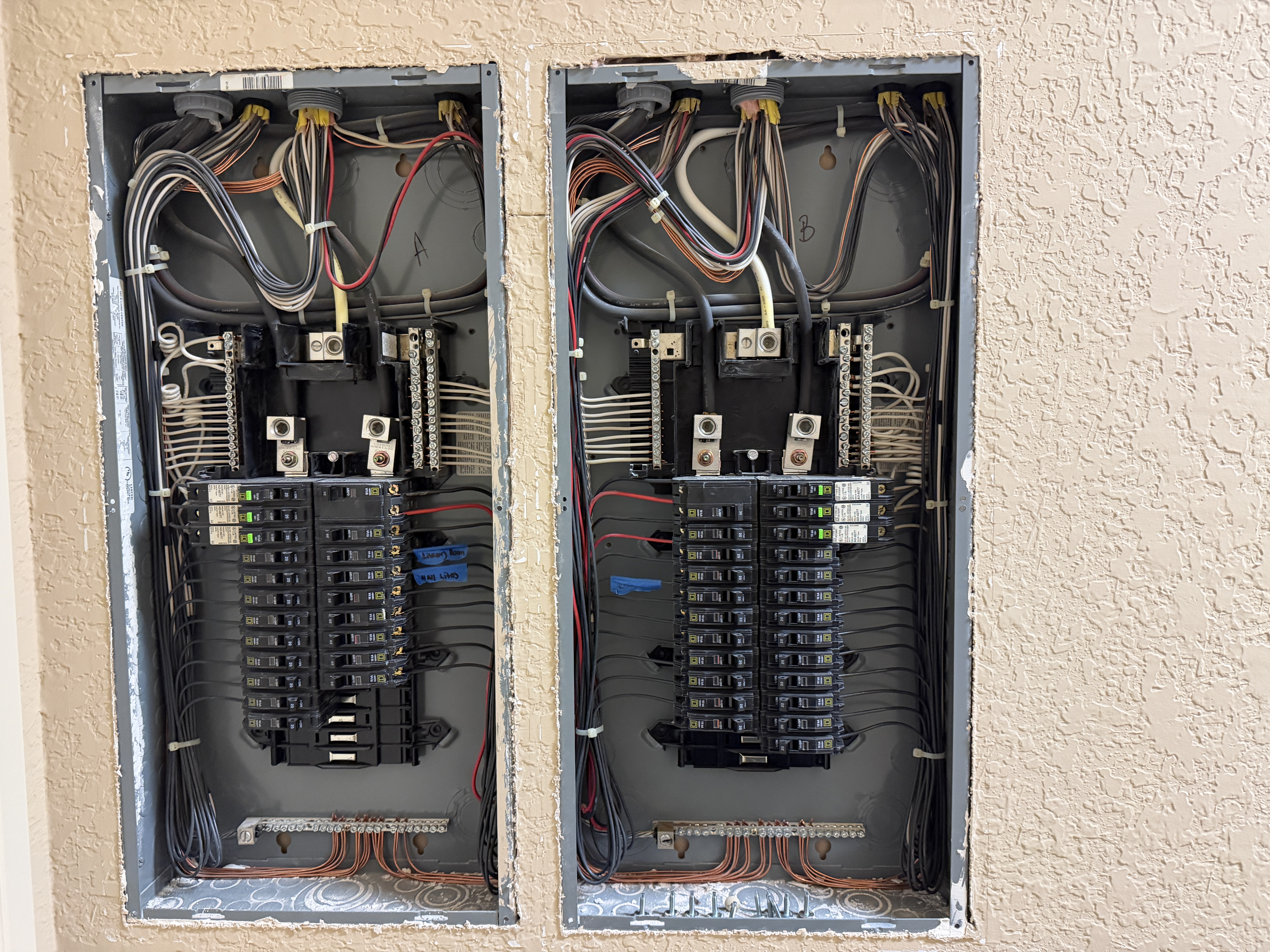 Exposed electrical service panels with labeled breakers inside a home