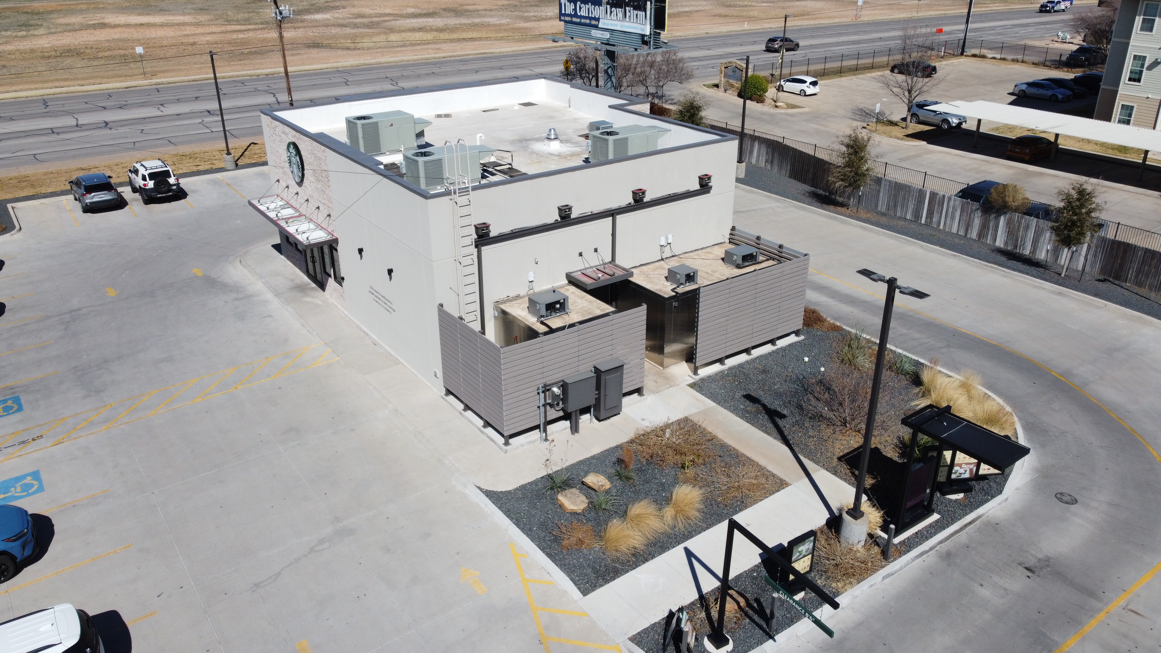 Aerial drone view of a commercial building with rooftop HVAC units and parking lot