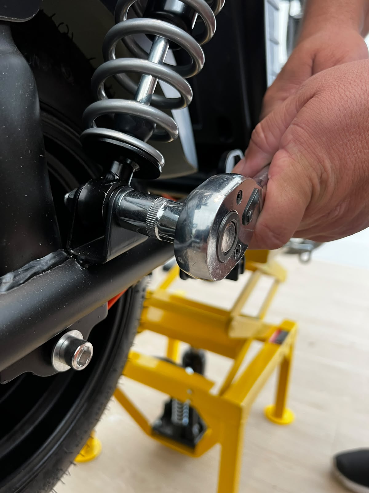 Mãos de técnico montando scooter elétrica preta sobre elevador hidráulico amarelo Vonder na oficina Four Eletric