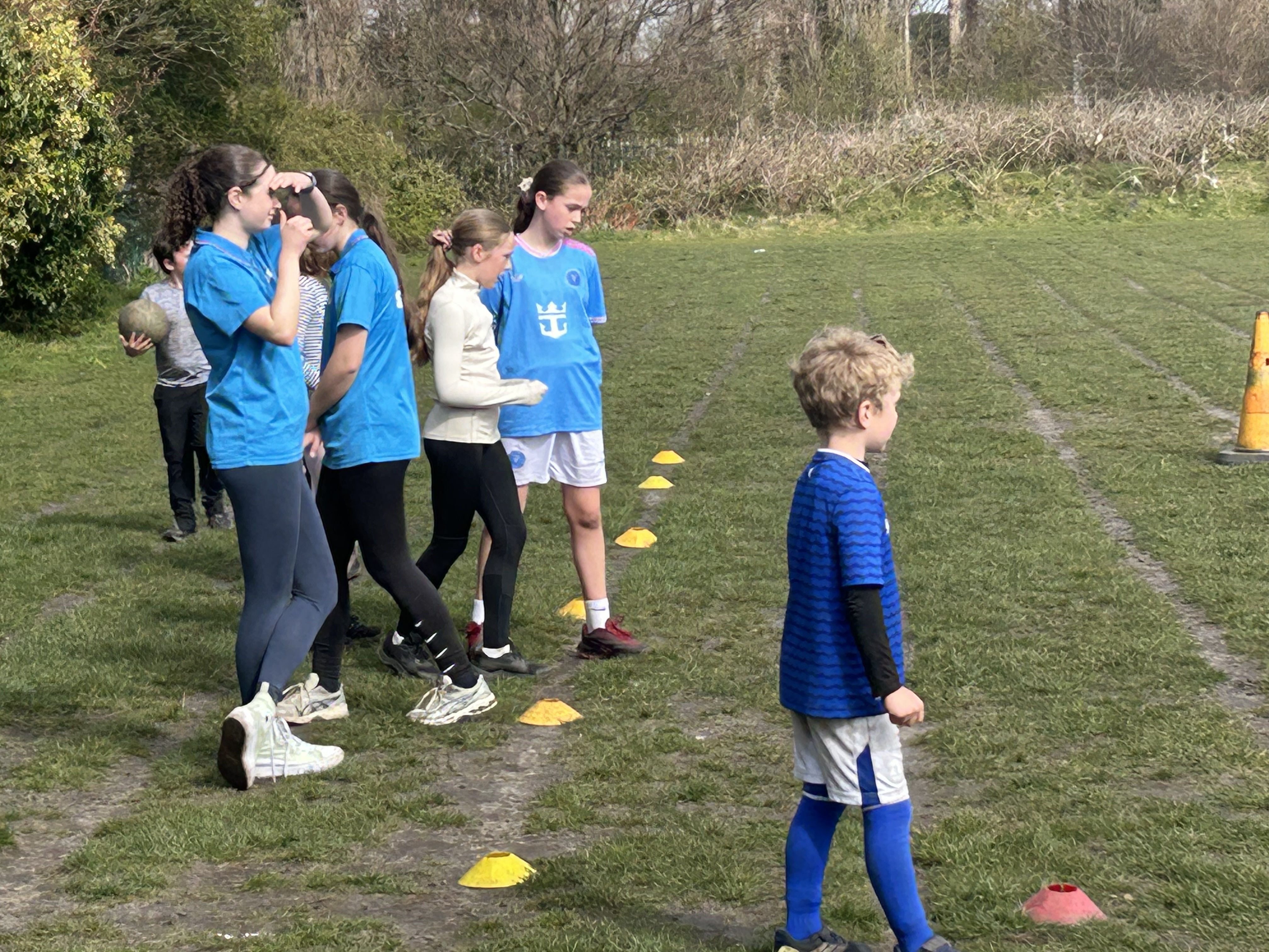 A young leader demonstrating a drill to children on the school field