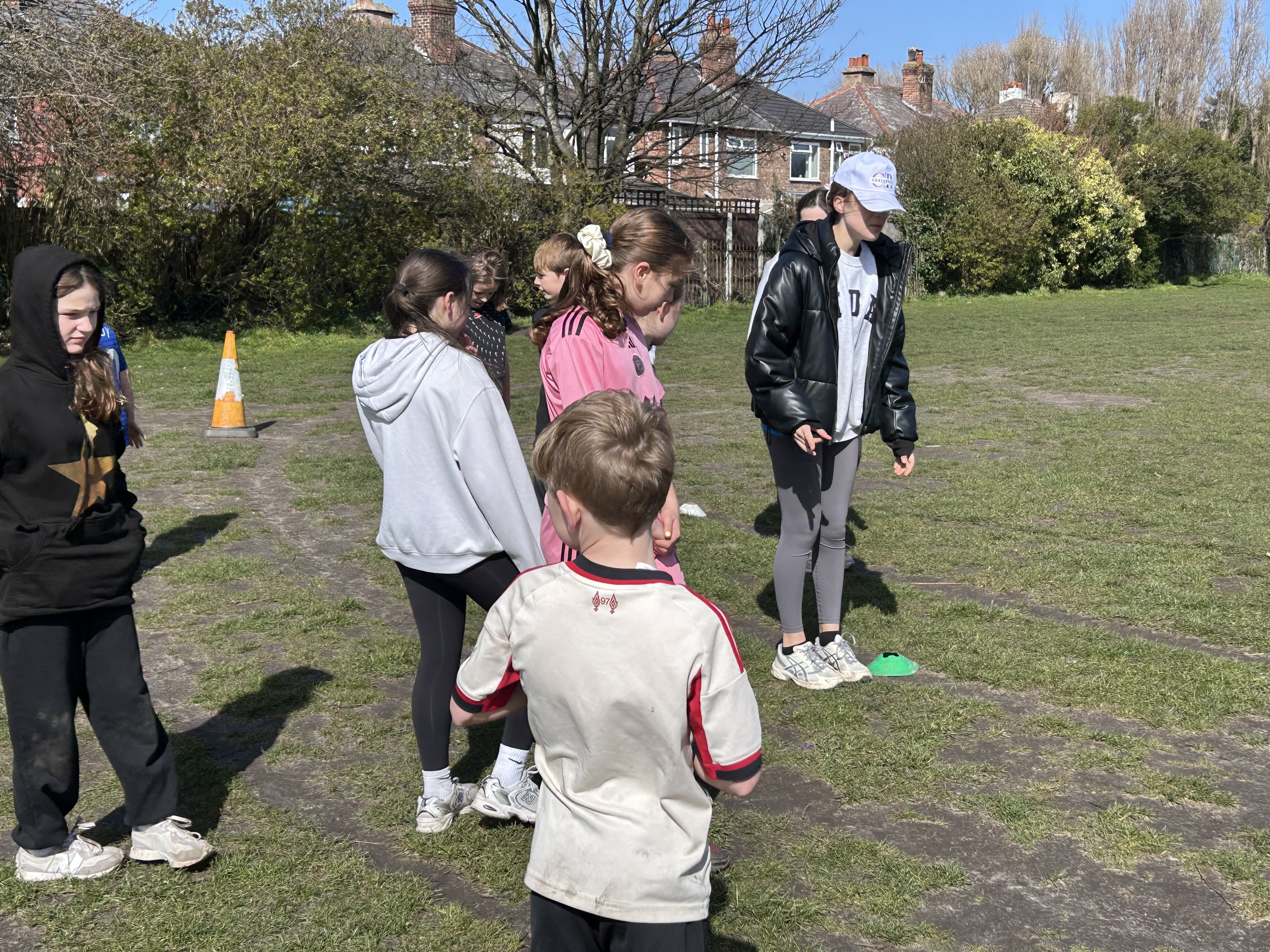 A young leader coaching a group of children on the field