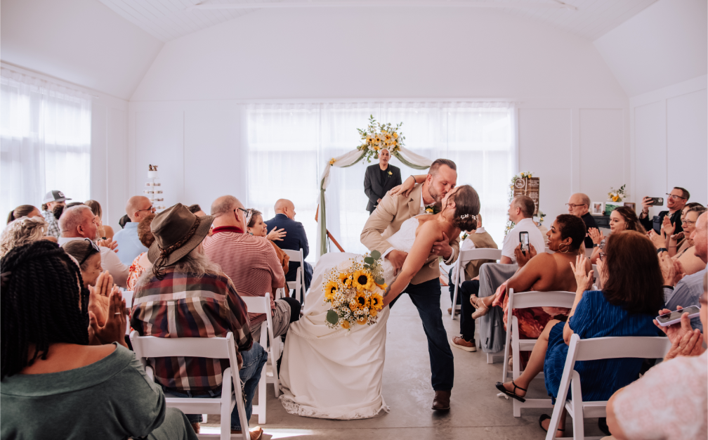A joyful ceremony kiss surrounded by family and friends.