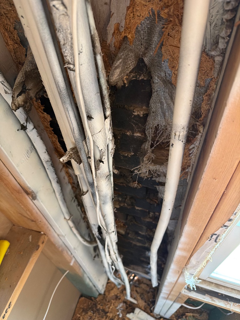 Fire-damaged wall cavity — melted wiring and scorched structure