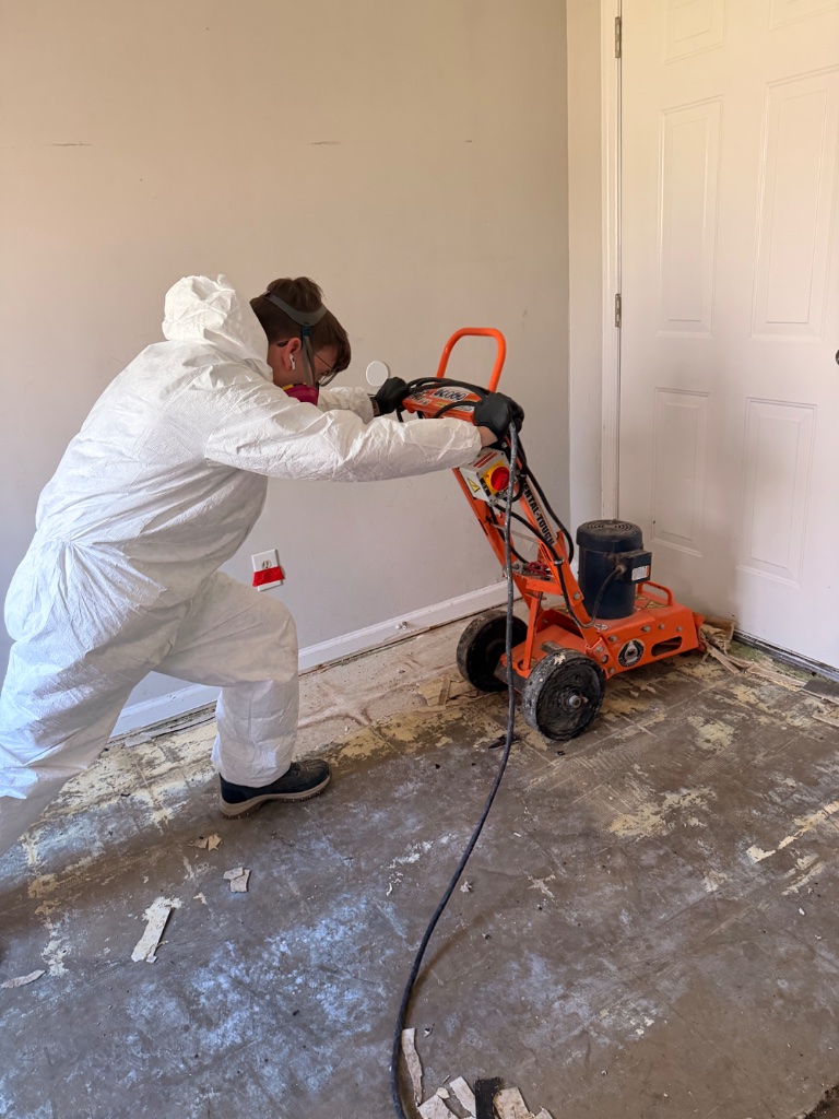 Asbestos flooring removal — floor grinder in full PPE