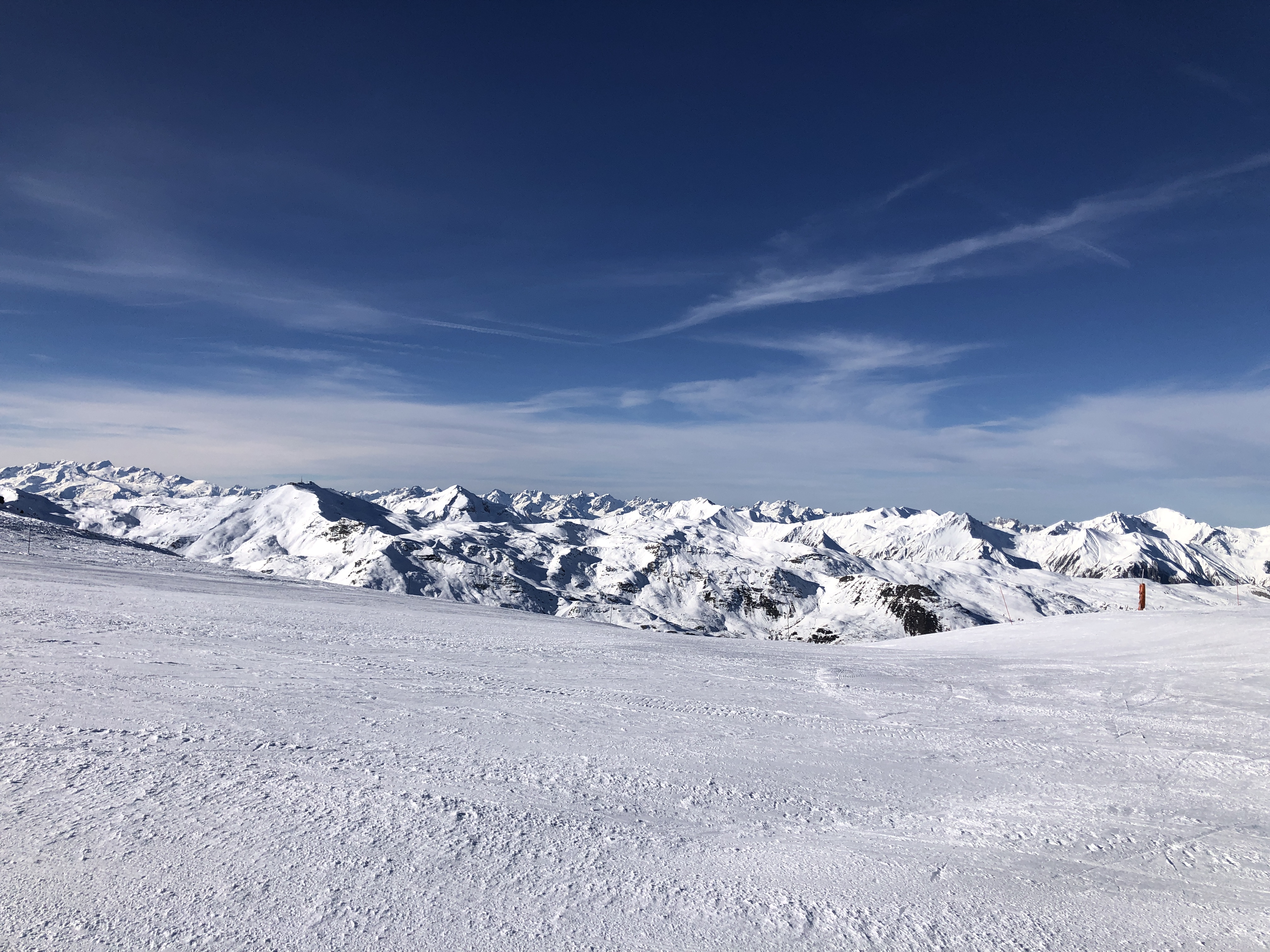 Groomed piste below a jagged mountain skyline