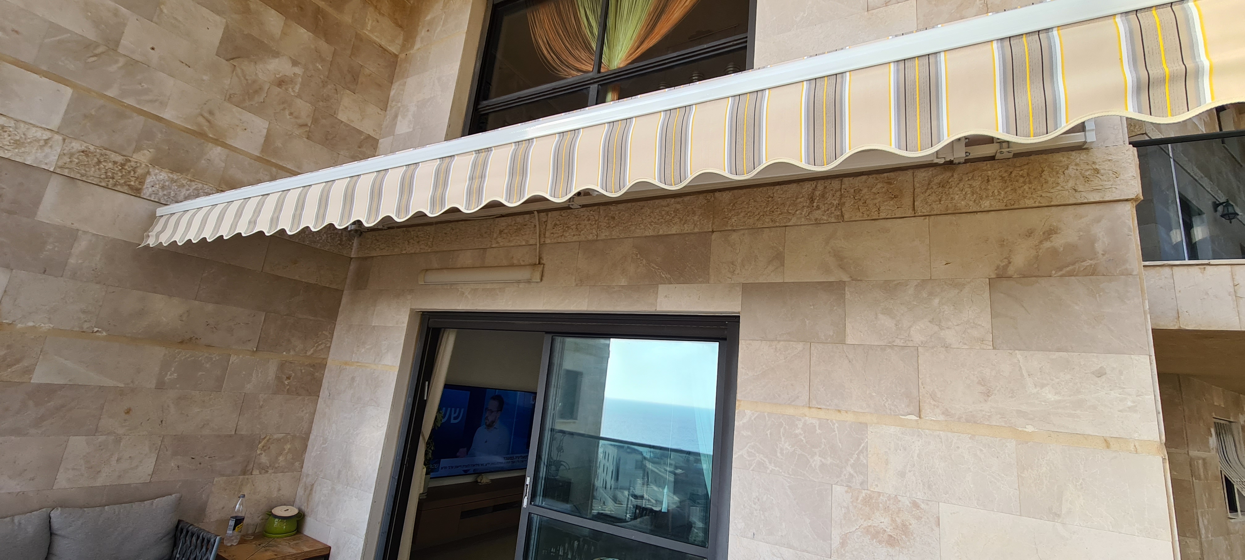 סוכך זרועות בפסי בז' עם וולן מסולסל — הצללה למרפסת מגורים
