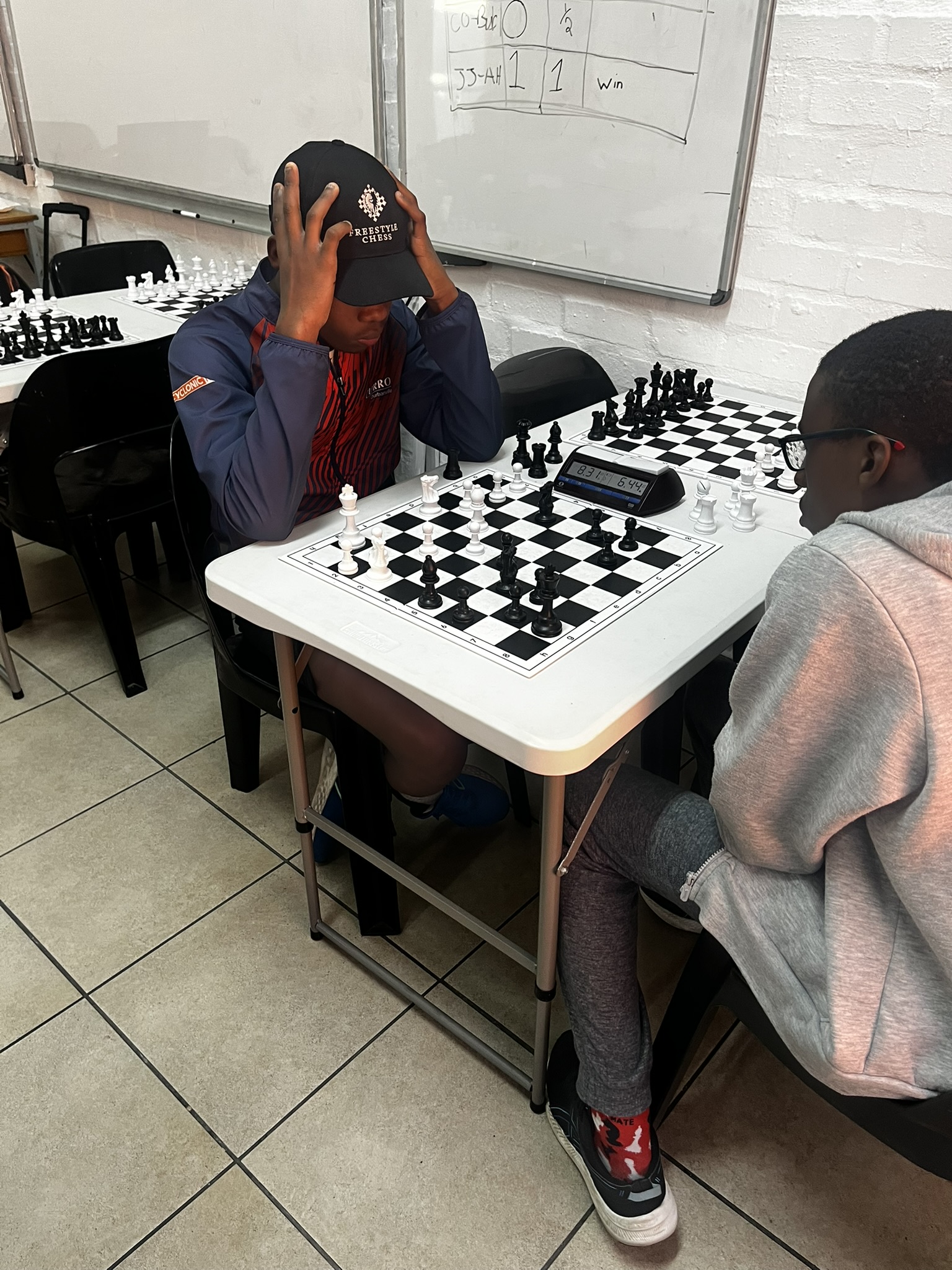 Two senior players competing across a board with a digital chess clock