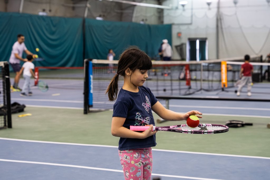 Young girl balancing tennis ball on racket