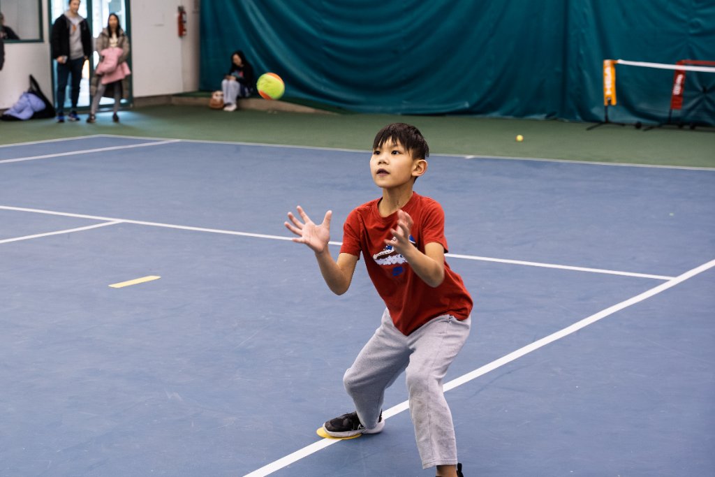 Boy catching tennis ball on court
