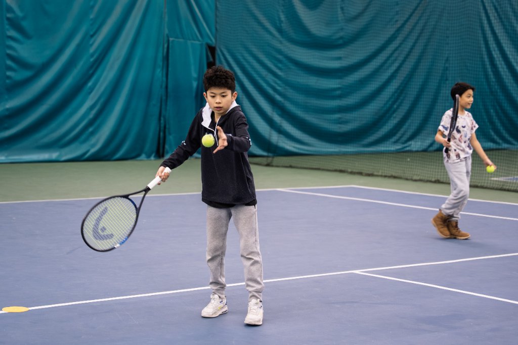 Boy hitting forehand with another player in background