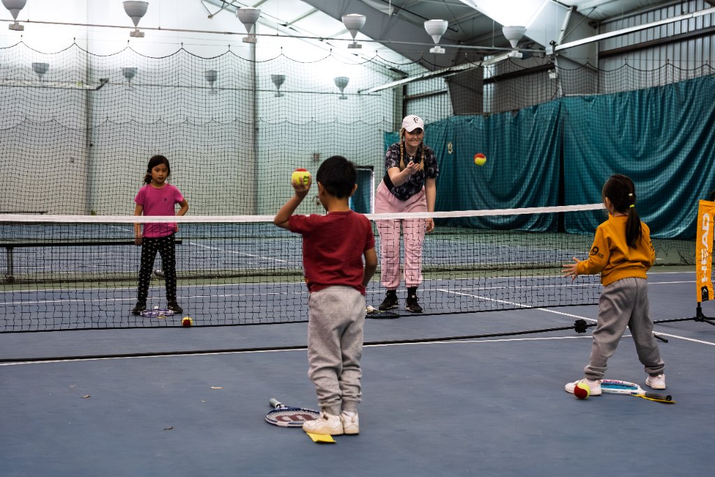 Tennis coach with kids at the net