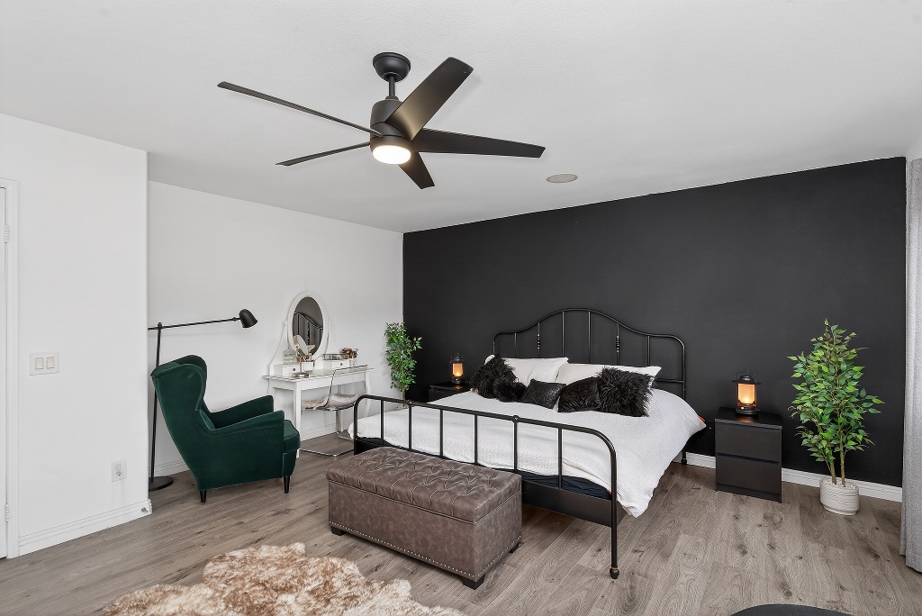 Master bedroom with black accent wall and ceiling fan