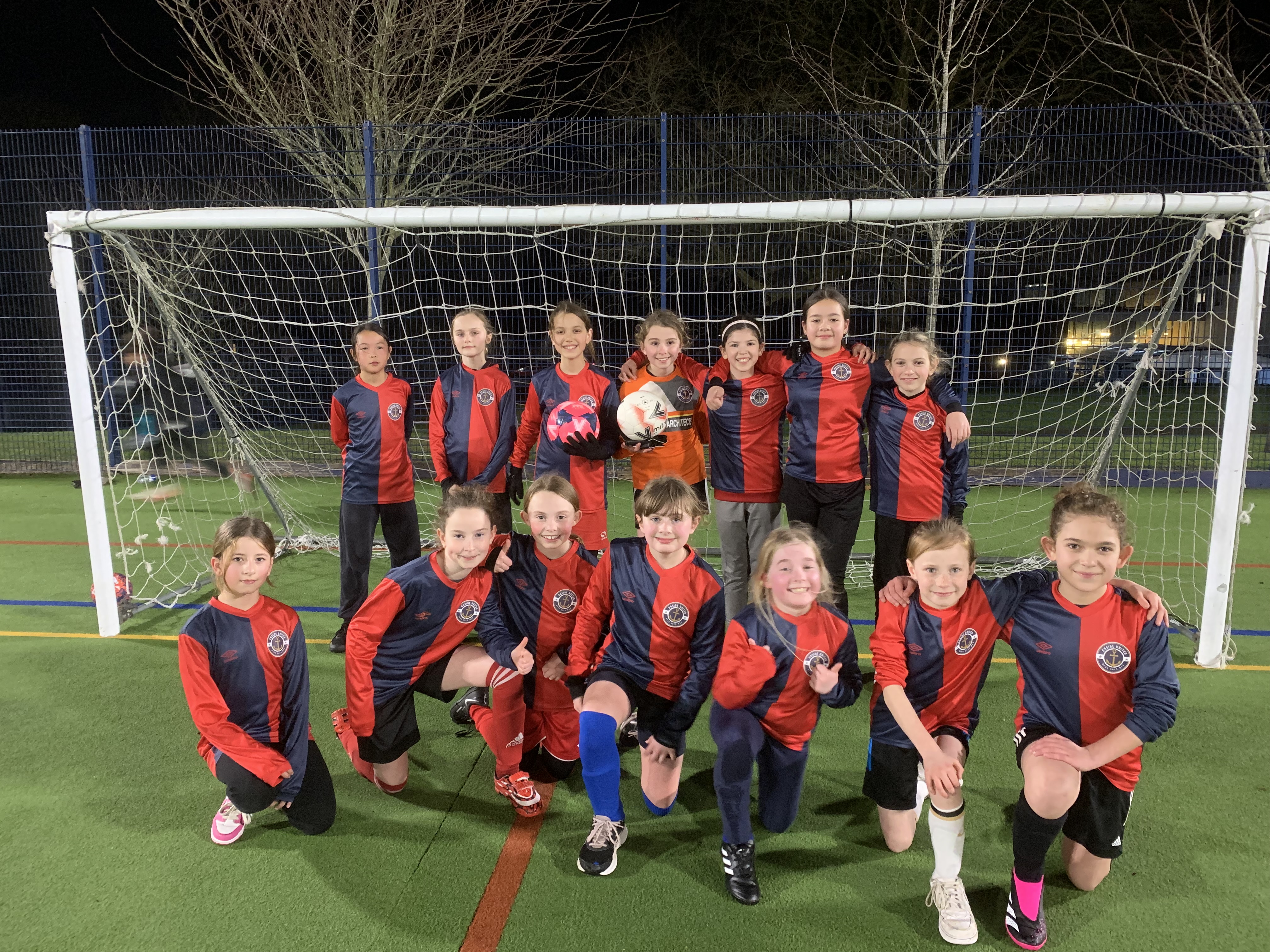 Onside girls' football team posing together on the pitch
