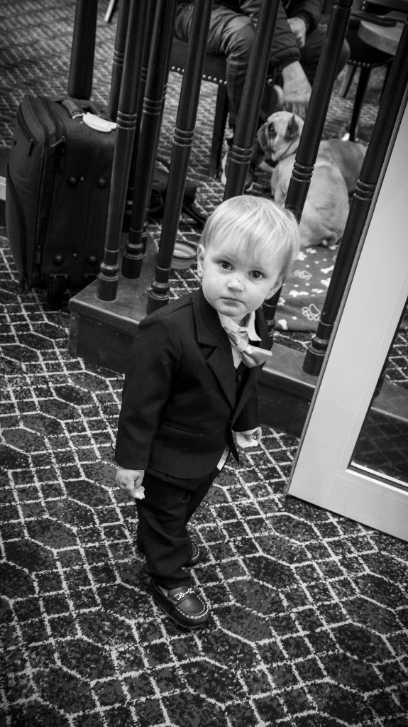 Young child in a formal black suit at a wedding venue