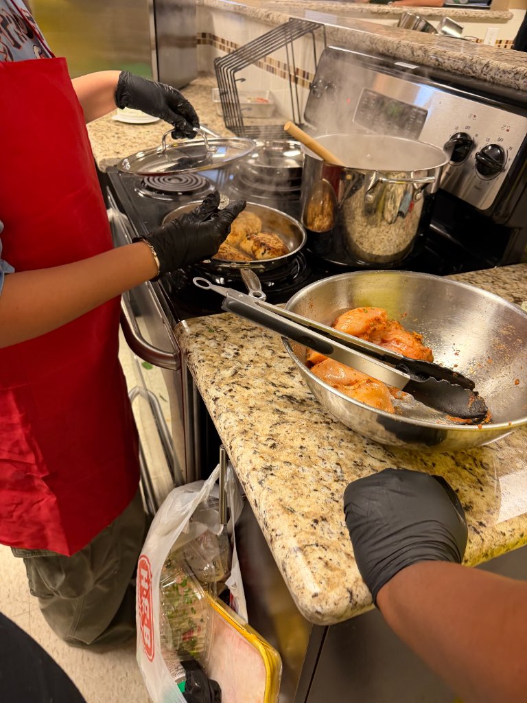 Cooking with a red apron and black gloves at the stove