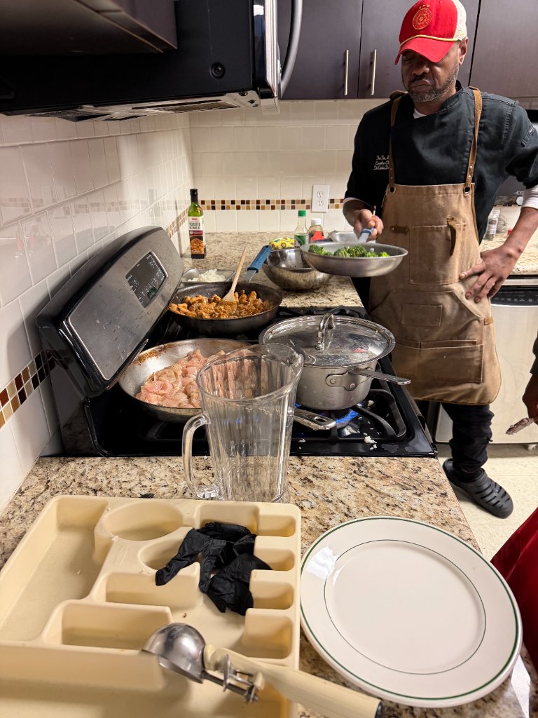 Chef sautéing broccoli in a stainless steel pan