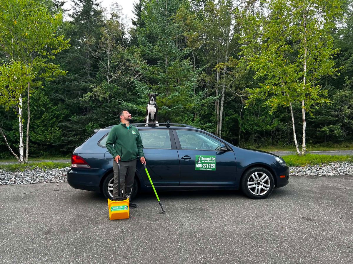 A Scoop I Do technician with the branded service vehicle and dog at Tucker Park