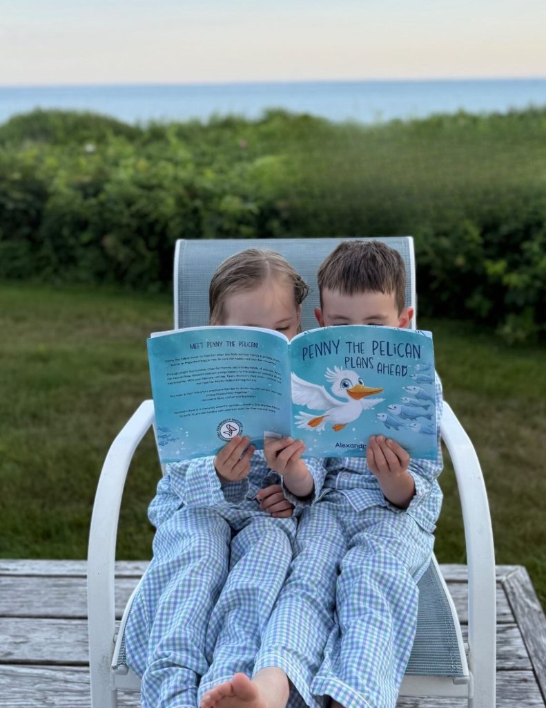 Two children reading Penny the Pelican Plans Ahead together in a beach chair