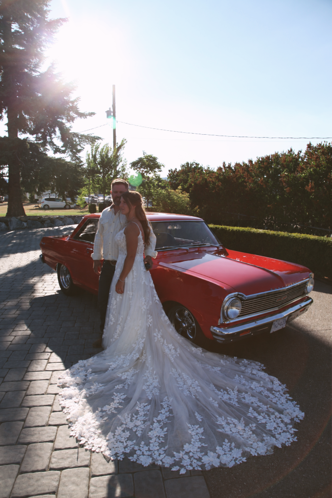 Wedding couple beside a vintage red car