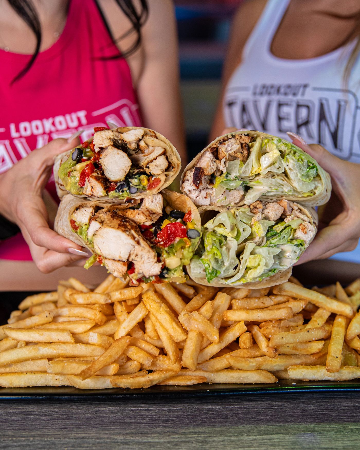 Two wraps cut open over a basket of fries