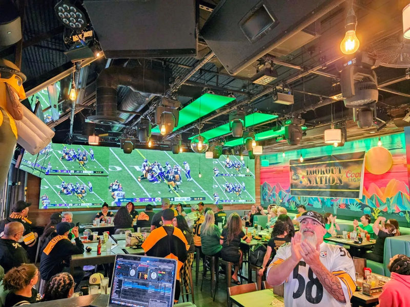 A packed Steelers watch party at Lookout Tavern, fans in black and gold under the LED screens