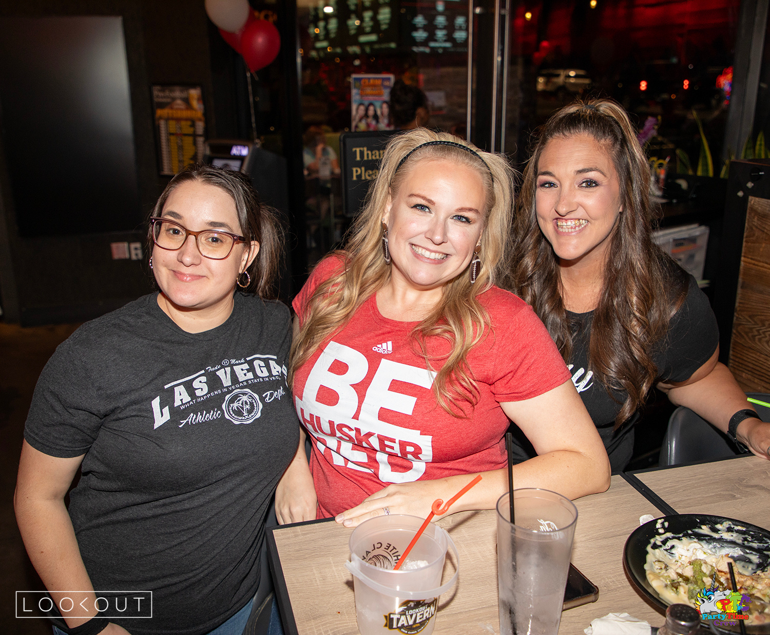 Friends in Husker red at a table on game day